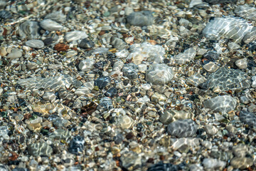 Beach with multicolored small round stones on a sunny day