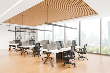 Modern coworking interior with office tables and pc computers near window