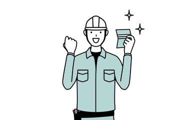 預金通帳を見て喜ぶヘルメットと作業着姿の男性