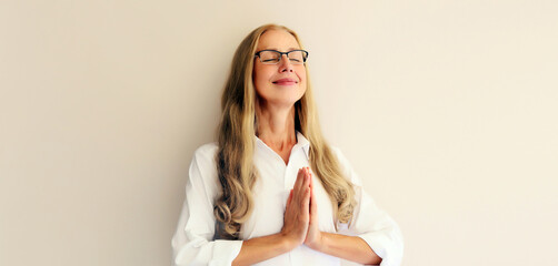 Calm relaxing healthy middle-aged woman meditates, practicing yoga on white background