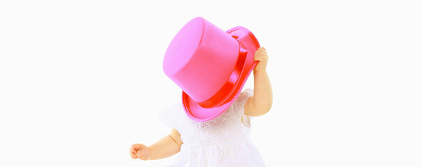 Cheerful baby playing with pink hat on the floor on white studio background