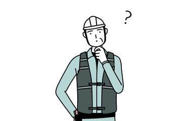 疑問を持って首をかしげるヘルメットと作業着姿のシニア男性技師