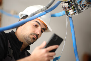 Electrician checking phone installing electrical system