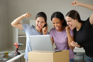 Three excited roommates checking laptop moving home