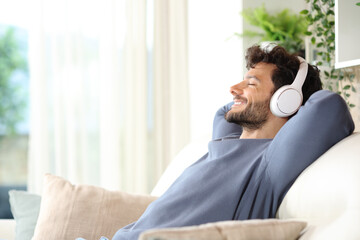Happy man listening music and relaxing on a couch