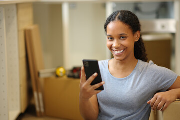 Happy black woman holding phone moving house