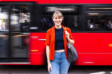 Woman with bag standing in front of moving bus at street
