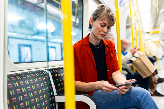 Woman using smartphone and siting in subway train