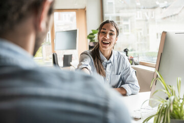 Cheerful businesswoman communicating with coworker at office