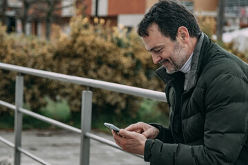 mature man using mobile phone on the street