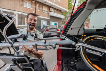 Happy disabled man loading handcycle in car trunk