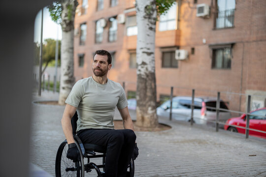 Man with disability sitting on wheelchair near building