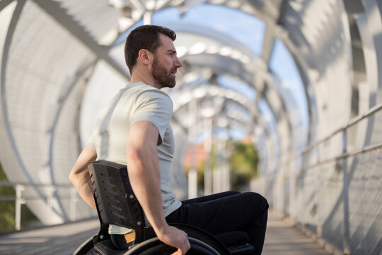 Man with disability sitting on wheelchair at bridge