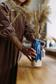 Potter decorating vase with pampas grass at desk