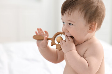 Cute baby boy with wooden rattle at home