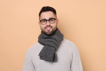 Smiling man in knitted scarf on beige background