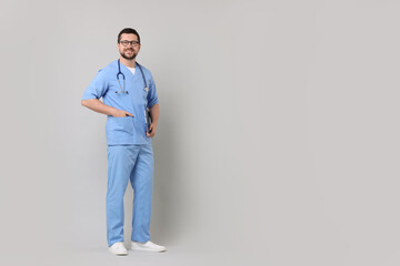 Fototapeta premium Full length portrait of smiling doctor on light grey background. Space for text