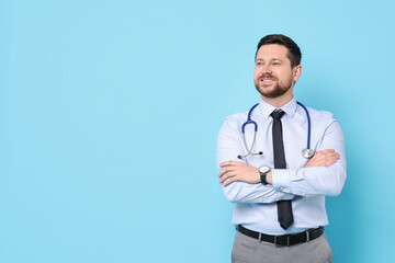 Smiling doctor with stethoscope on light blue background. Space for text