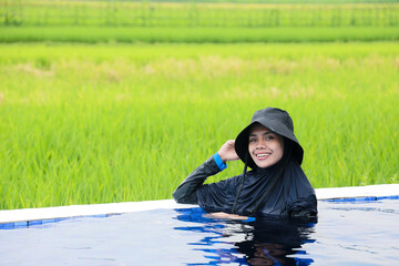 Portrait of a happy young Asia woman relaxing in the infinity edge pool at resort