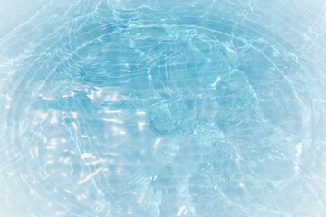 Blue water with ripples on the surface. Defocus blurred transparent blue colored clear calm water surface texture with splashes and bubbles. Water waves with shining pattern texture background.	