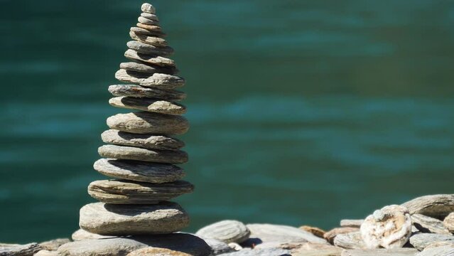 Smooth, round, flat stones stacked into a Cairn along a riverbank