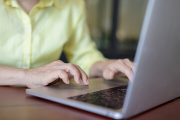 Fototapeta premium Business women in a yellow shirt working on laptop in office