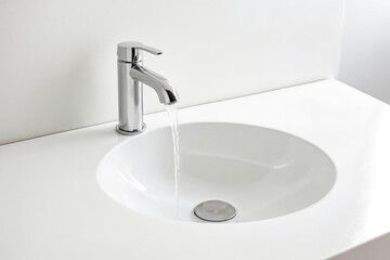 Close-up of a faucet with water flowing into a white sink