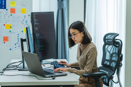 Asian prompt engineer develop coding app with software data sitting in front of computer monitor at office