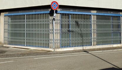 No stopping sign, with an abandoned street corner shop  with the folding security gates closed....