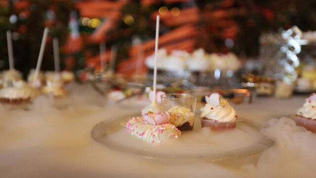 Luxury candy bar. 4K video with a premium elegant candy bar for events with plates of sweet floating on a carbonic ice water surface with smoke coming out between them.