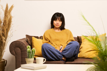 A woman is sitting on a couch with a book in her lap