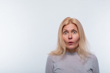 European woman with blond hair looks in surprise on a white background with copy space
