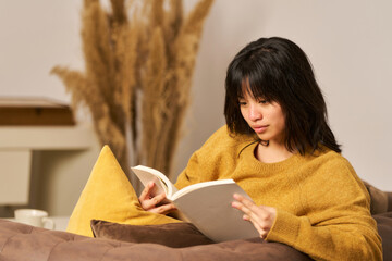 A woman is reading a book on a couch