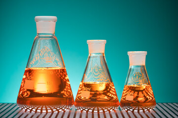 Erlenmeyer glass flasks placed in a laboratory table with orange liquid