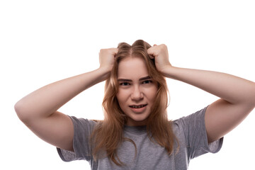 Fototapeta premium Portrait of a confused teenage girl with blond hair in a gray T-shirt on a white background