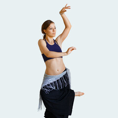 Beautiful young woman in stylish clothes dances tribal fusion oriental dances on an isolated light background. Tribal Fusion Belly Dance