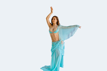 beautiful girl in a sexy blue costume dances oriental belly dancing on an isolated white background
