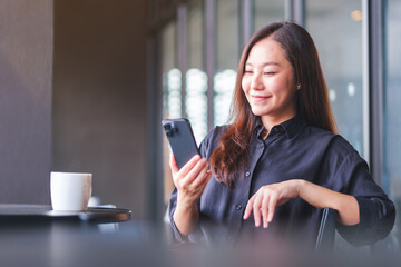Portrait image of a young woman holding and using mobile phone in cafe
