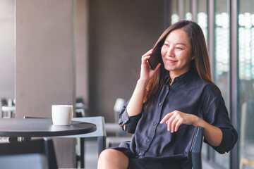 Portrait image of a young woman talking on mobile phone in cafe