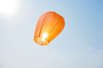 Single Orange Sky Lantern Floating in Blue Sky