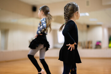 Two Young Girls Practicing Dance in Classroom with Mirrors and Hardwood Floor