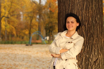 A beautiful girl in a raincoat against the backdrop of a bright autumn park. The concept of unity with nature. Vibration of beauty color
