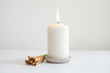 White candle burning on a white surface