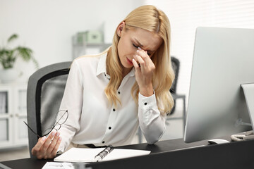 Overwhelmed woman with glasses at table in office