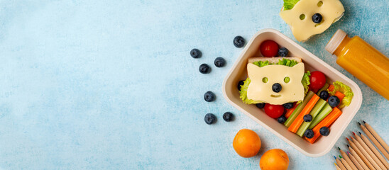 Back to school background. Kids school lunch box with funny fox sandwich with cheese, and fresh vegetables, carrot, tomatoes, celery, blueberries and apricots, orange juice. Pencils. copy space.
