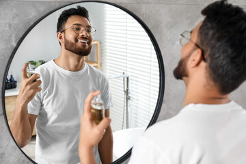 Fototapeta premium Man spraying luxury perfume near mirror indoors
