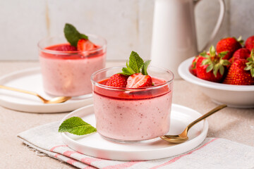 Table with couple of dessert, Strawberry panna cotta made with roasted strawberries, delicious, creamy dessert with sauce and fresh berries. Homemade.