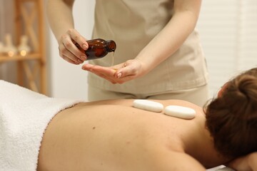 Aromatherapy. Woman receiving back massage with oil in spa salon, closeup