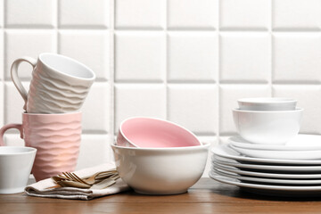 Beautiful ceramic dishware, cups and cutlery on wooden table