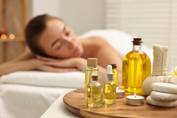 Aromatherapy. Woman relaxing on massage couch in spa salon, focus on bottles of essential oils,...